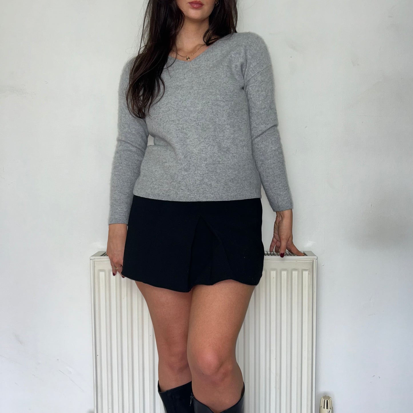 grey knit jumper shown on a model wearing a black mini skirt and black boots