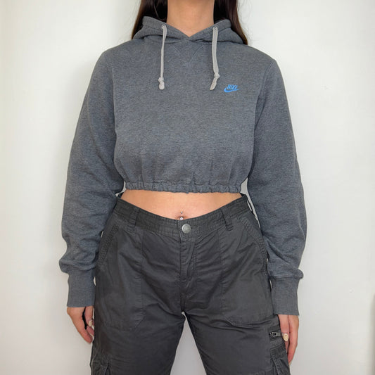 dark grey cropped hoodie with small blue nike logo shown on a model wearing grey cargo trousers 