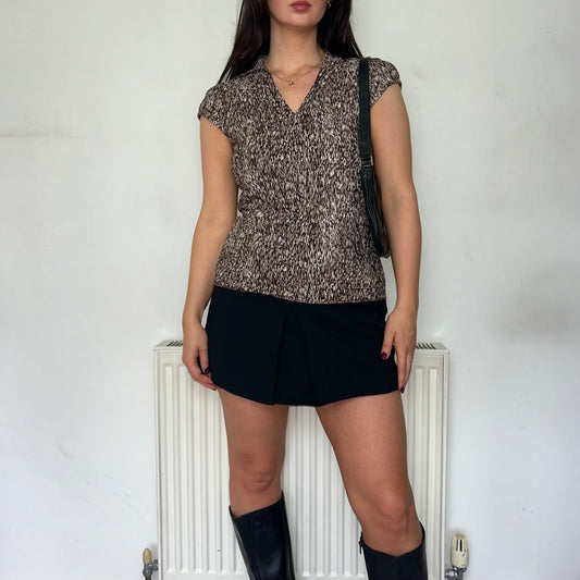 brown and beige short sleeve blouse shown on a model wearing a black mini skirt and black boots with a black shoulder bag