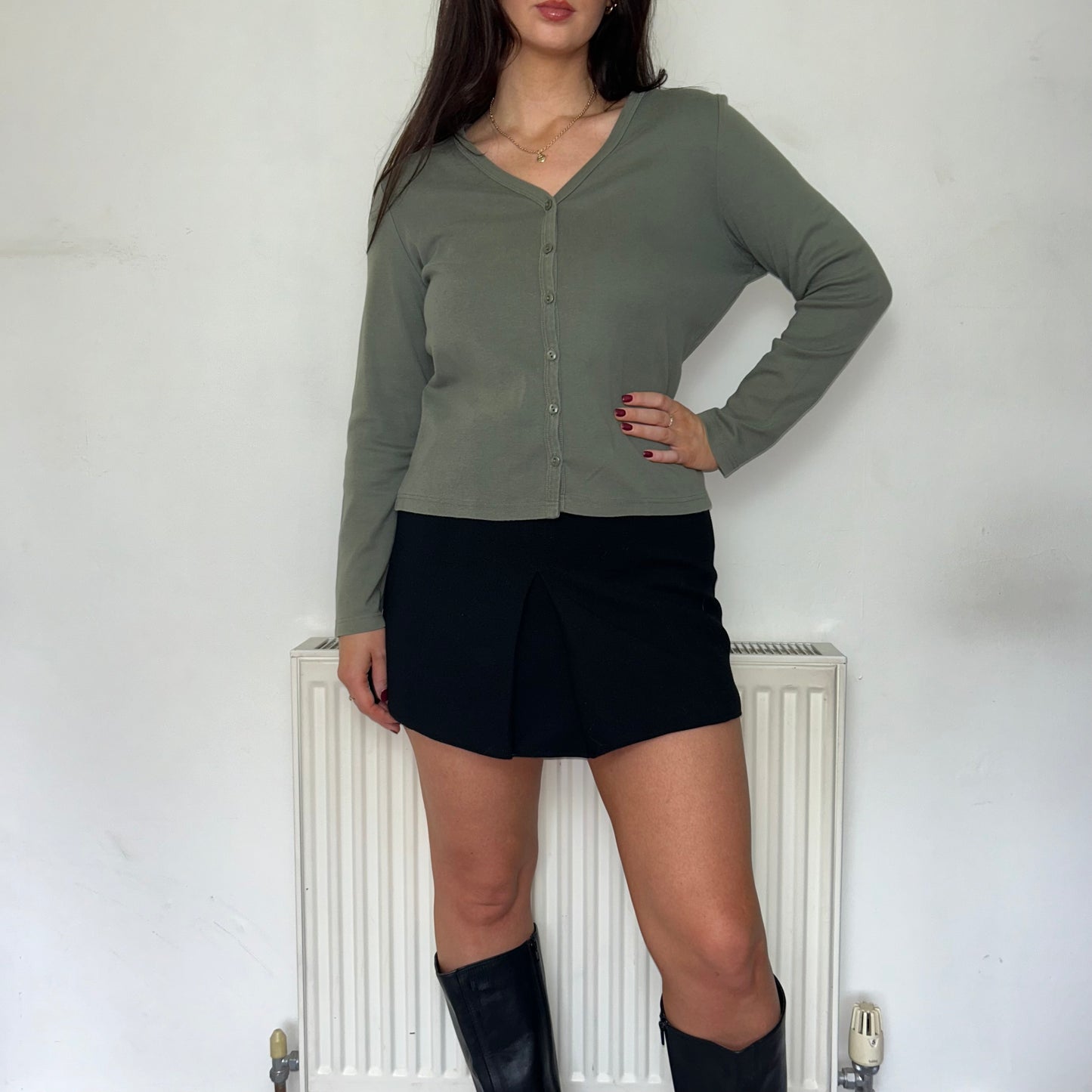 green button up long sleeve top shown on a model wearing a black skirt and black boots