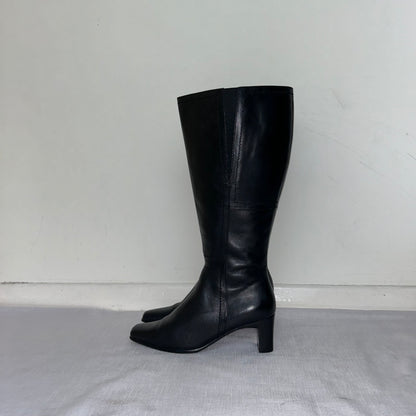 black knee high leather boots shown on a white background