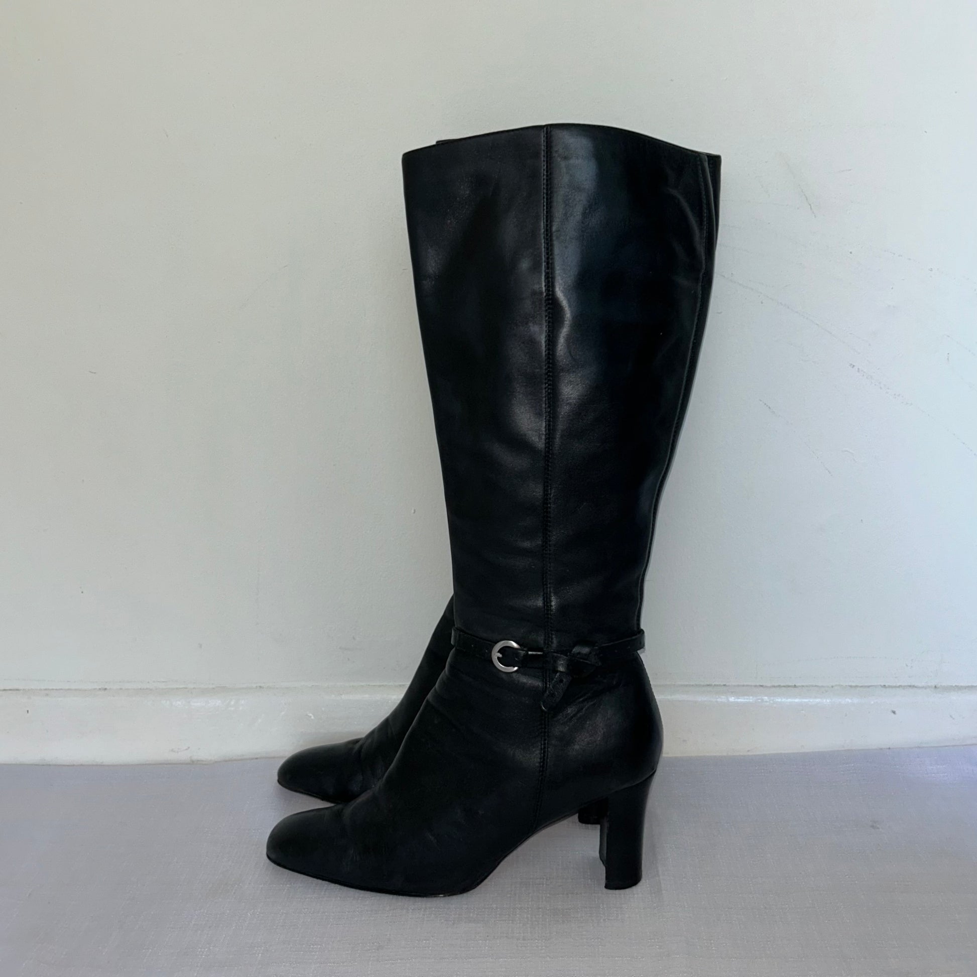 black knee high leather buckle boots on a white background