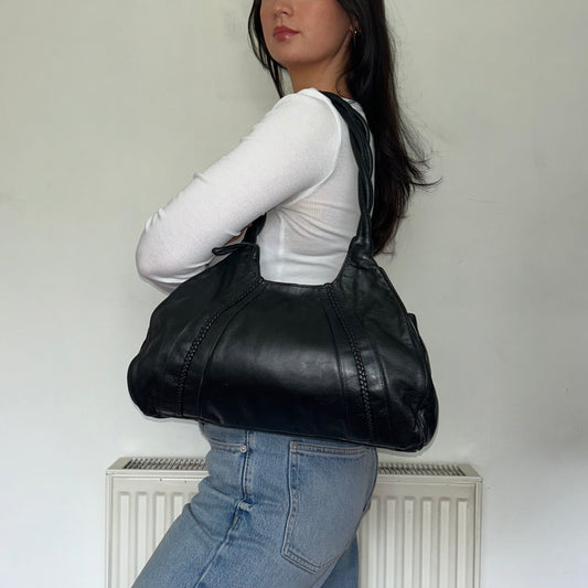 black slouchy leather bag shown on a models shoulder