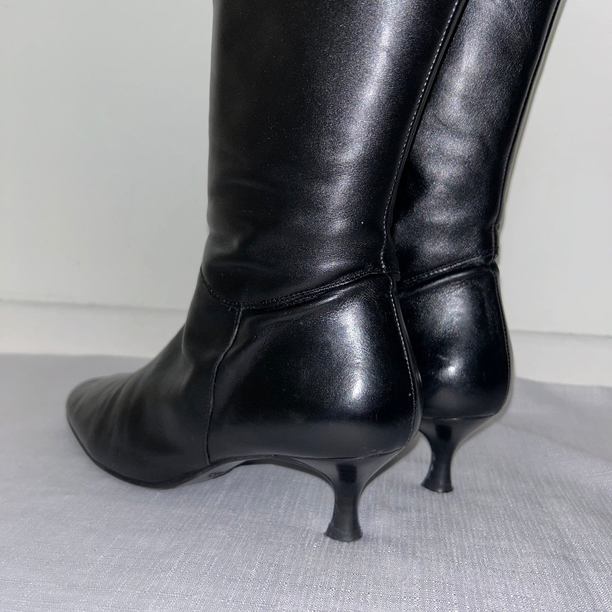 heels of black knee high boots shown on a white background