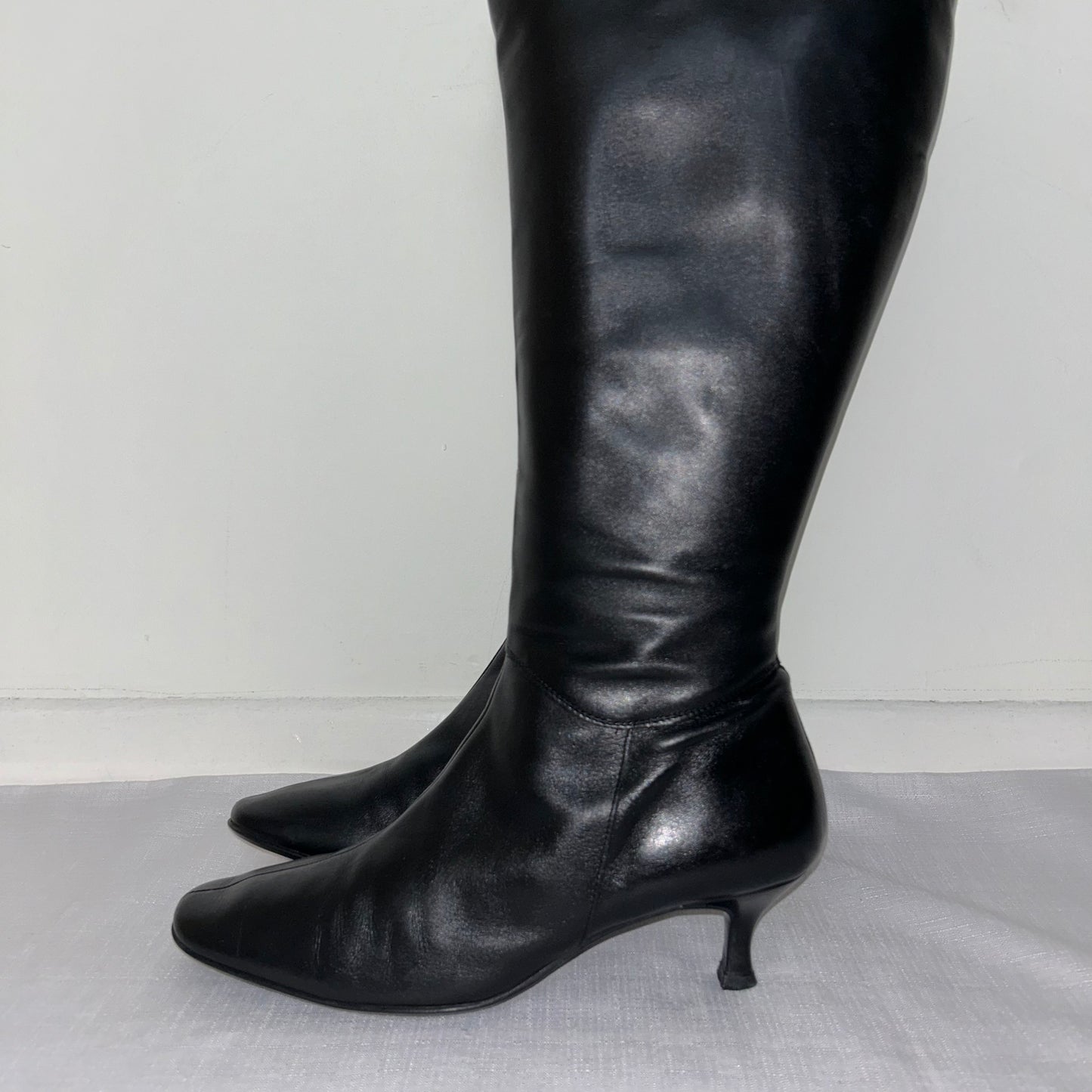 toes of black knee high boots shown on a white background