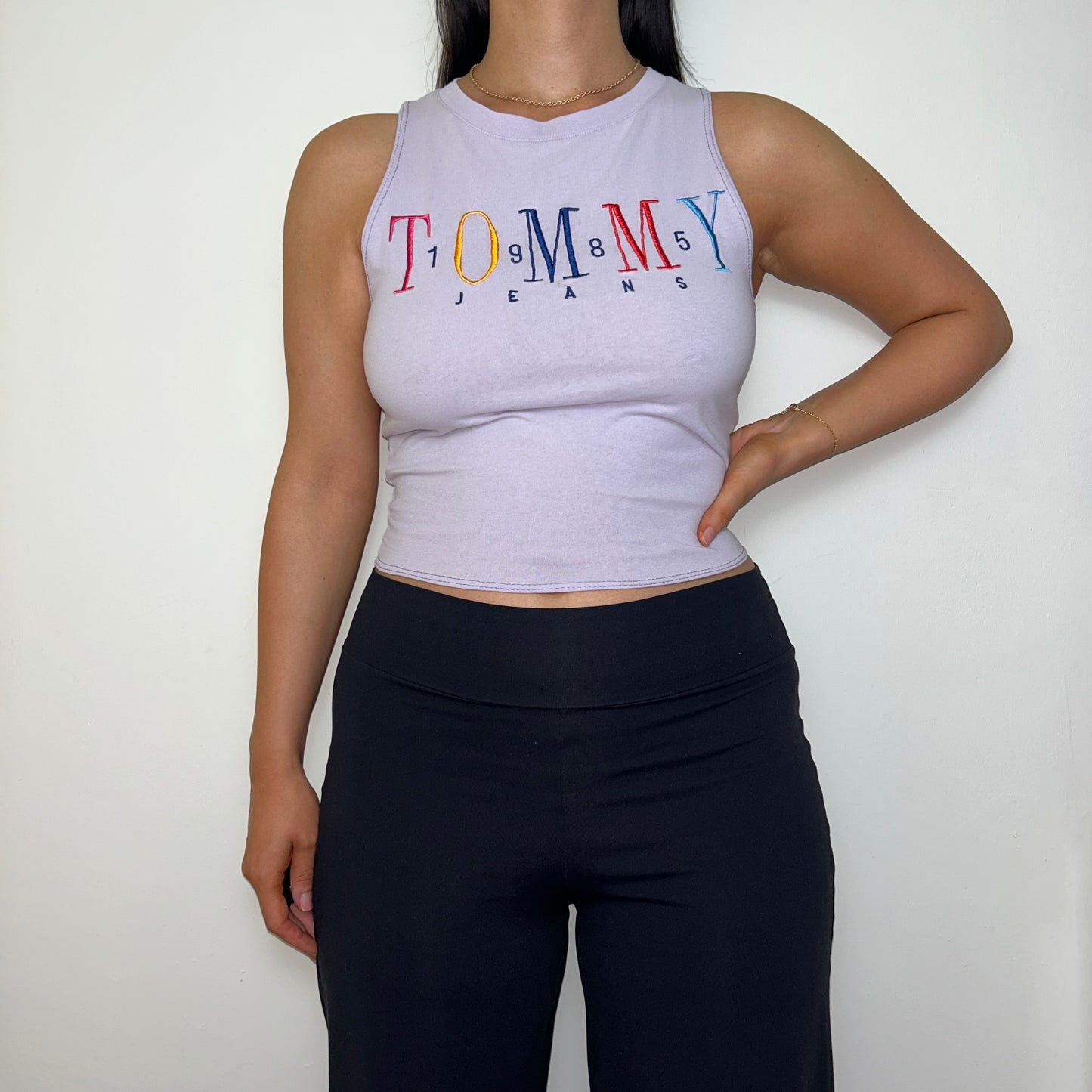 lilac short sleeve crop top with tommy jeans logo shown on a model wearing black trousers