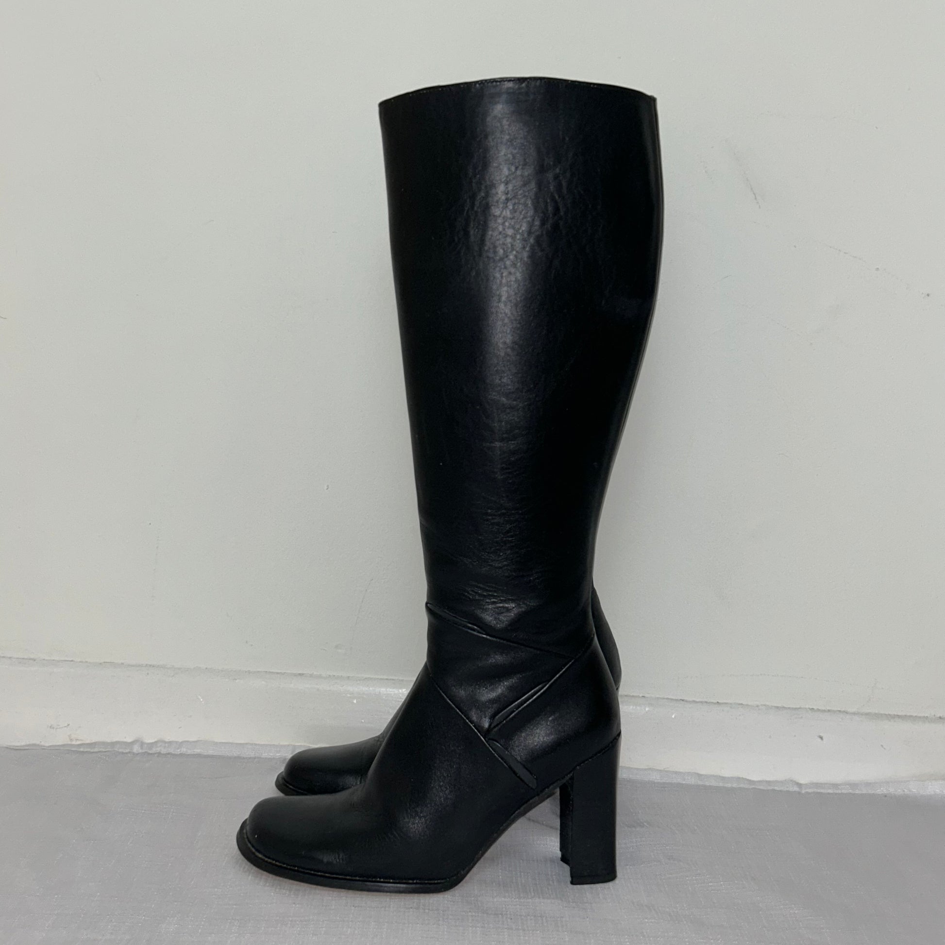 black knee high leather boots shown on a white background