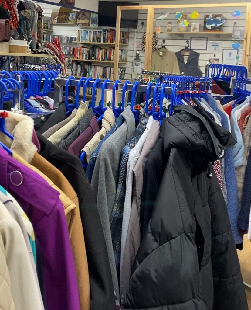 a photo of a shop with blue clothing hangers with different garments on the rail