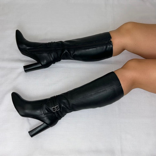 black knee high boots with double silver buckle shown on a models legs laid on a white background