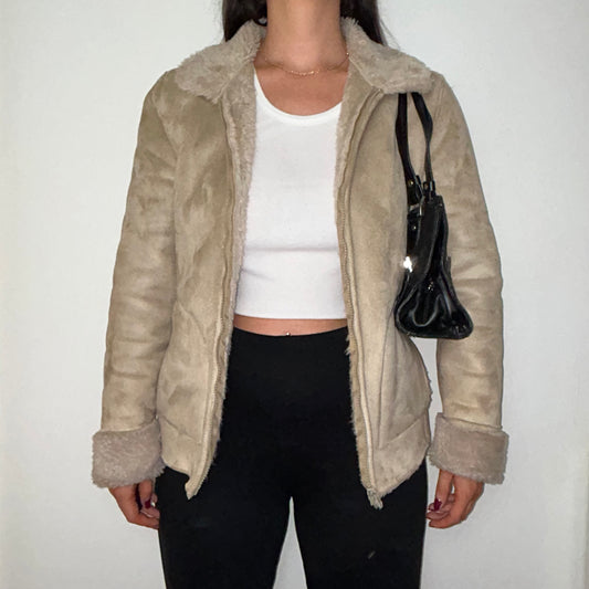 beige faux fur coat shown on a model wearing a white crop top and black trousers and a black shoulder bag