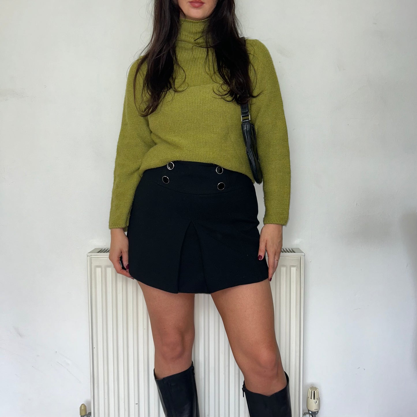 green high neck knit jumper shown on a model wearing a black mini skirt and black shoulder bag and black boots