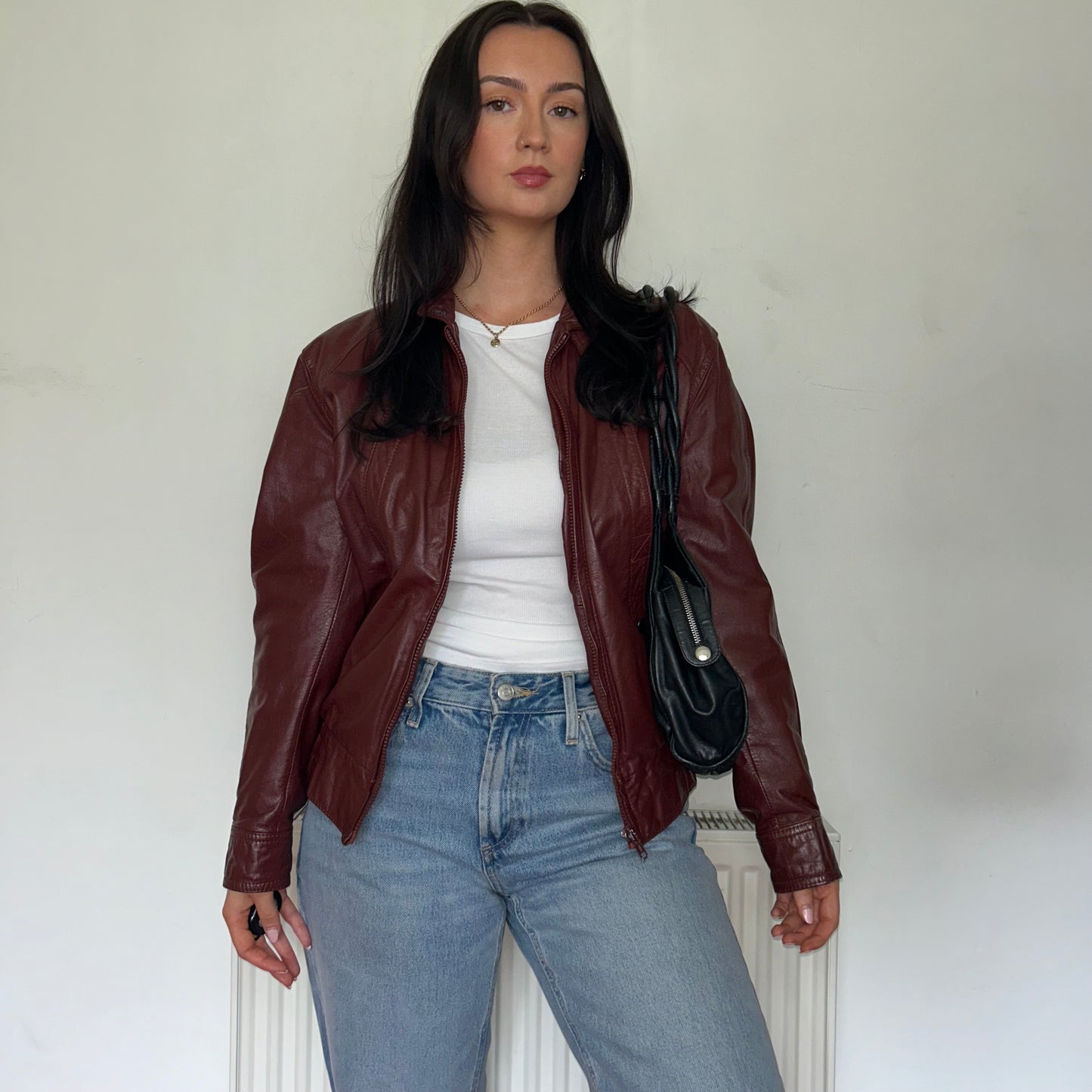 burgundy vintage leather jacket shown on a model wearing a white top and blue jeans