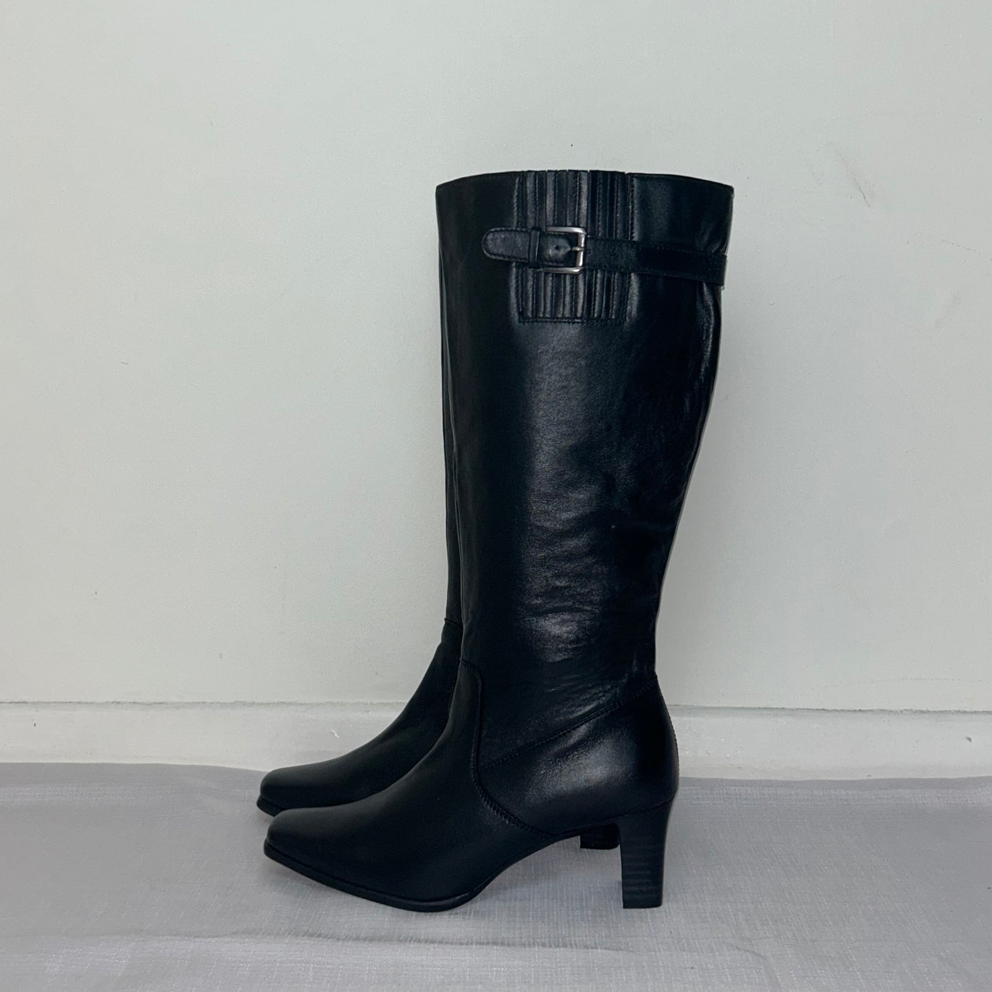 black knee high silver buckle boots shown on a white background