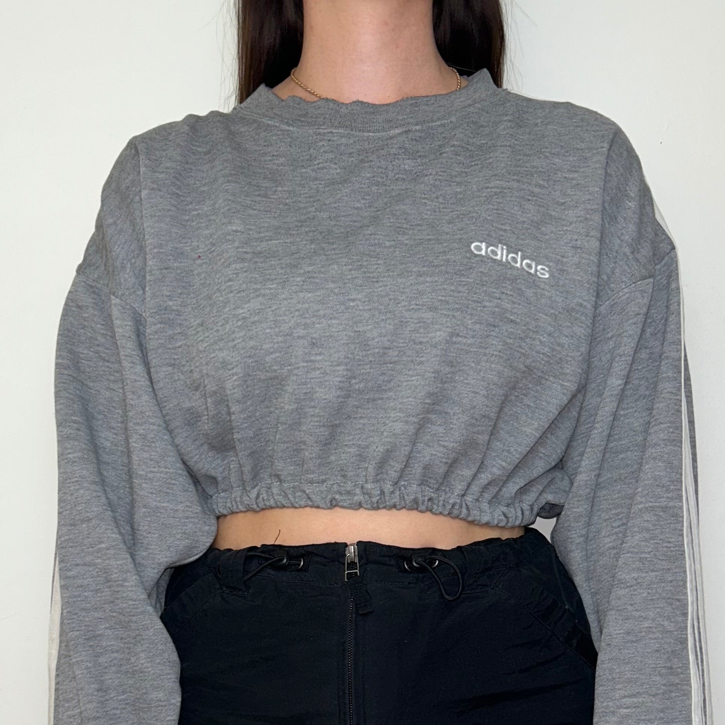 close up of grey cropped sweatshirt with white adidas logo shown on a model