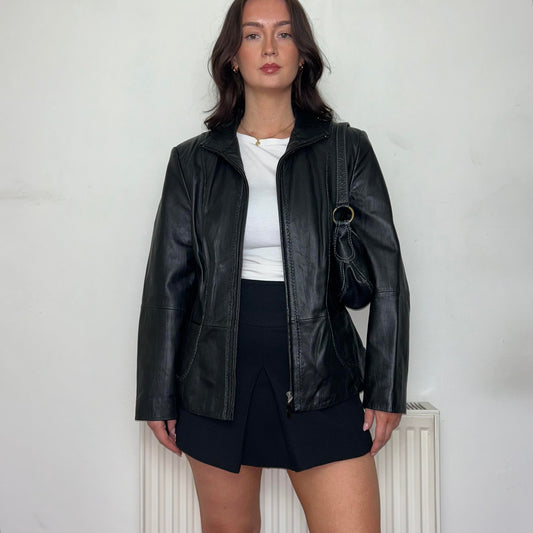 black leather vintage bomber jacket shown on a model wearing a white top and black mini skirt
