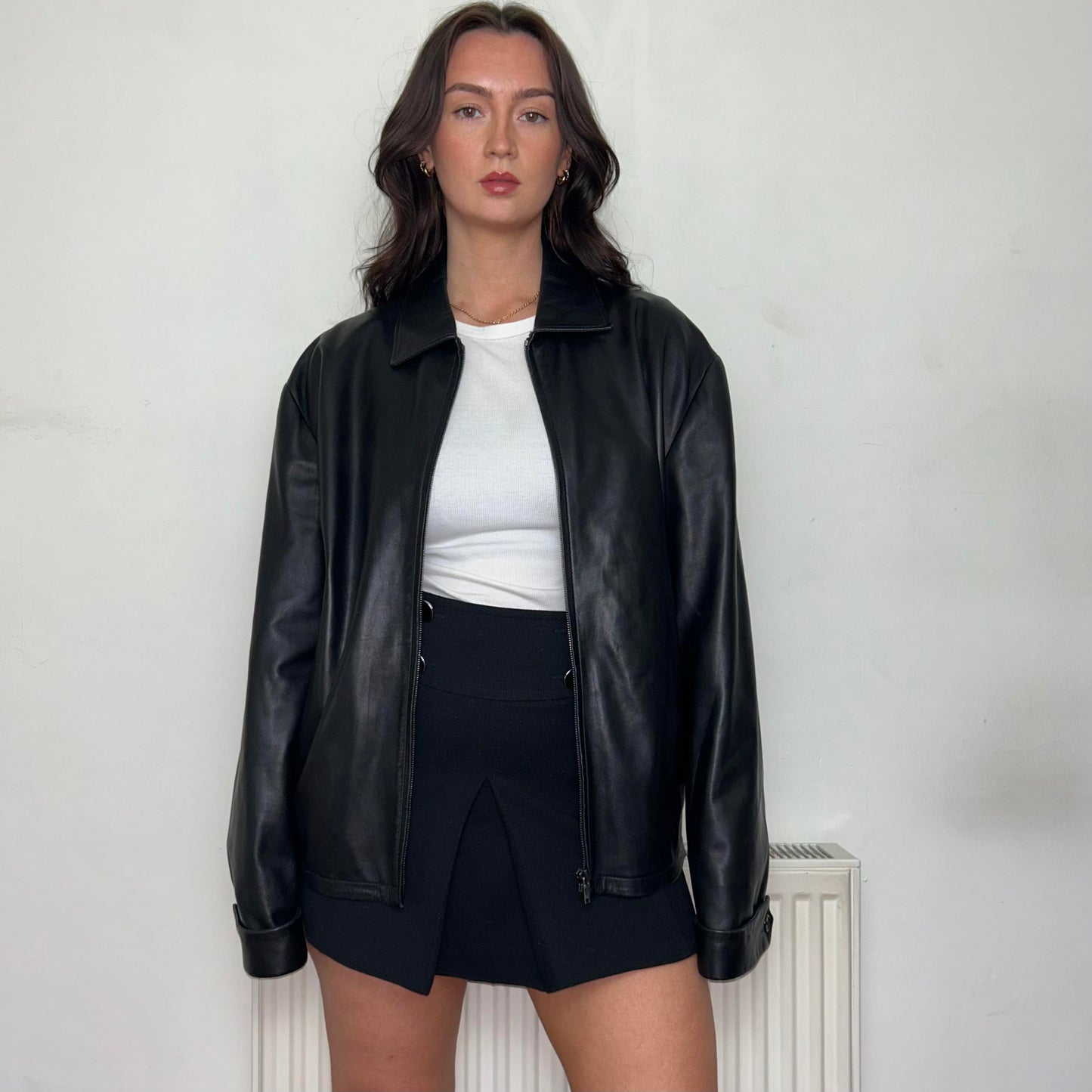 vintage oversized black leather bomber jacket shown  on a  model wearing a white crop top