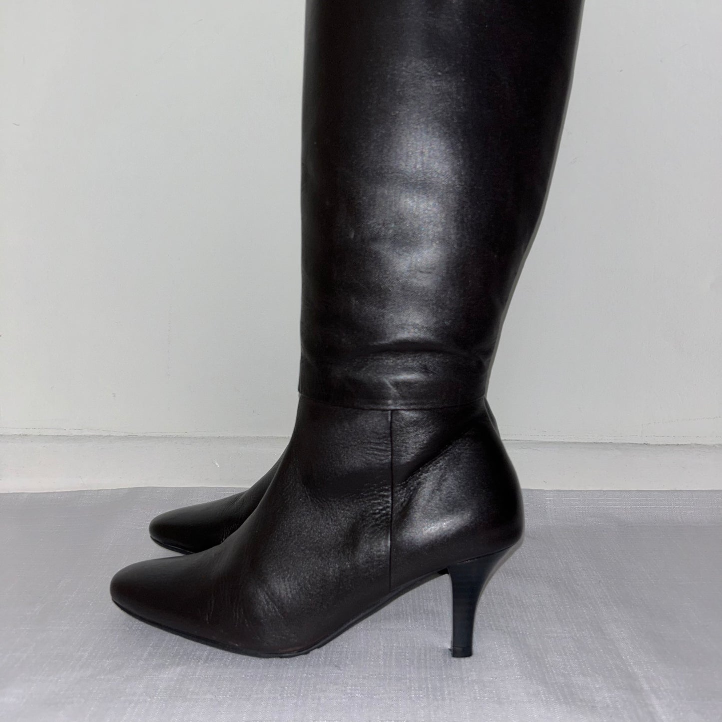 close up of dark brown leather knee high boots shown on a white background