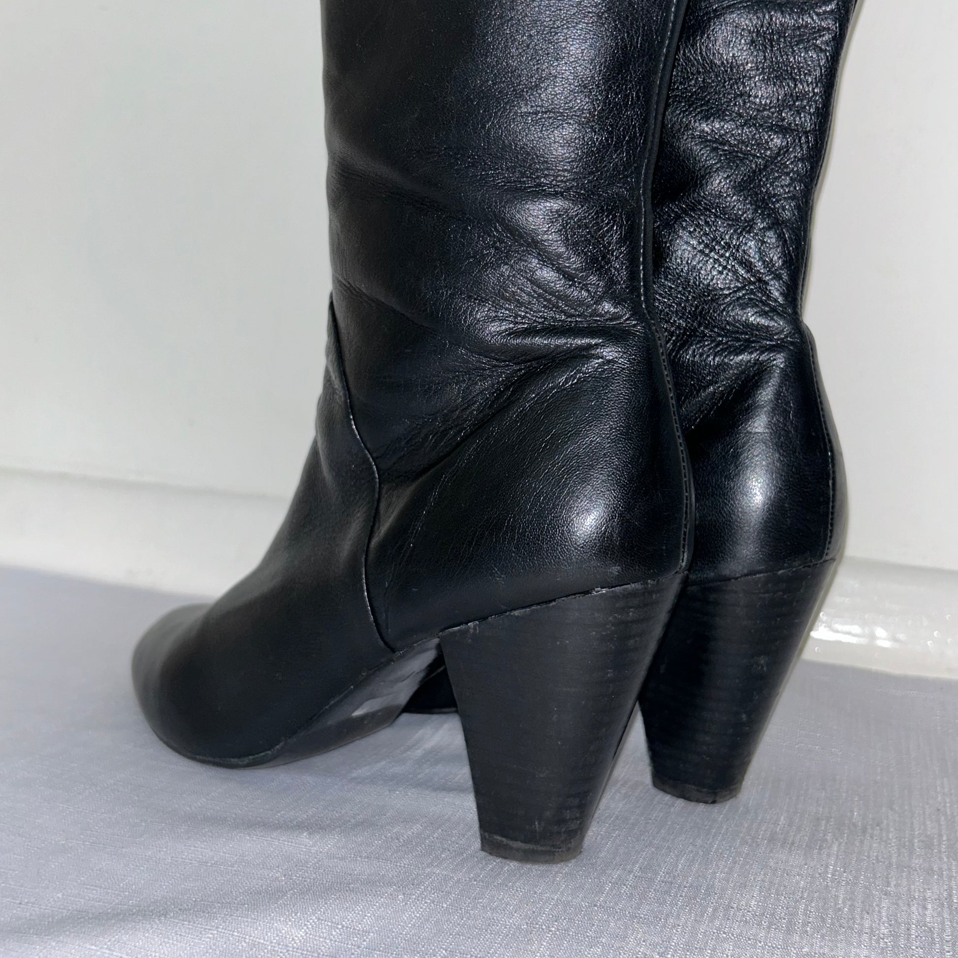 heels of black knee high boots shown on a white background