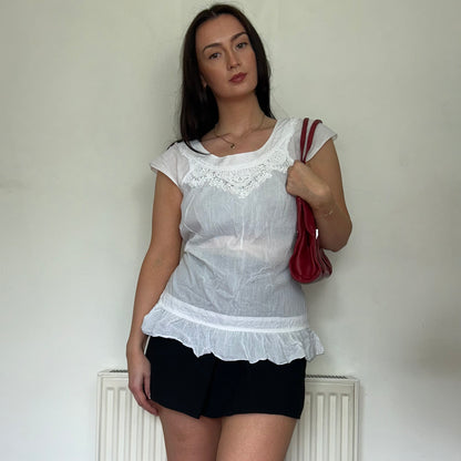 close up of vintage white blouse top shown on a model wearing a black mini skirt