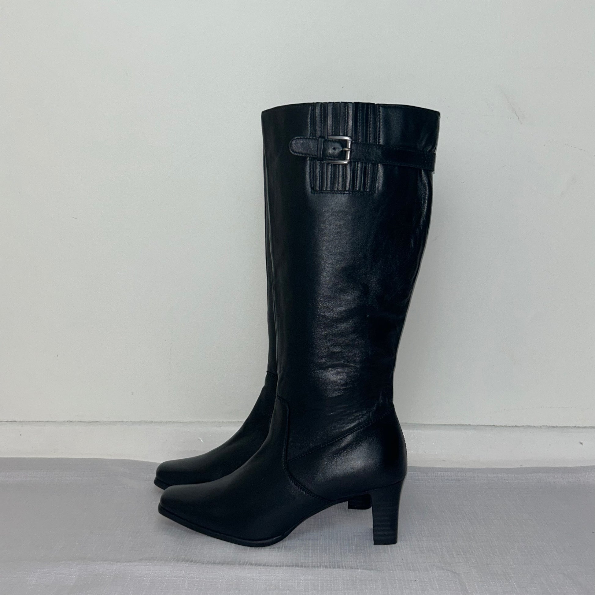 black knee high buckle boots shown on a white background