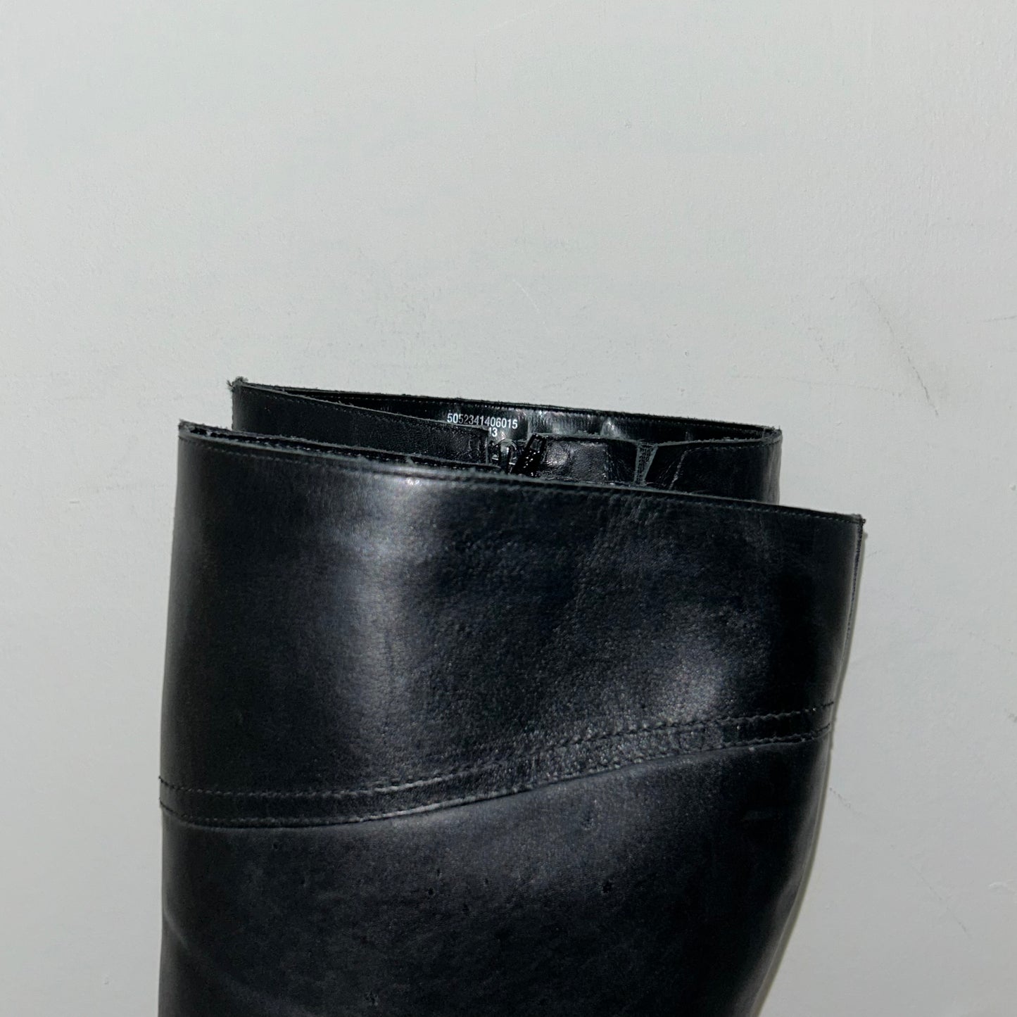 close up of black knee high leather boots shown on a white background