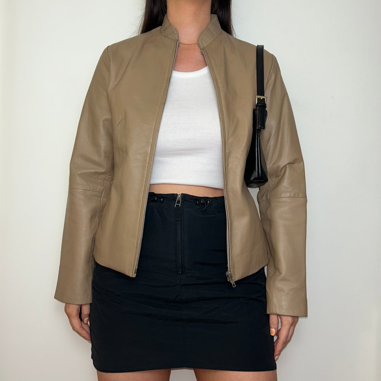 tan beige real leather jacket shown on a model wearing a white crop top and black mini skirt and a black shoulder bag