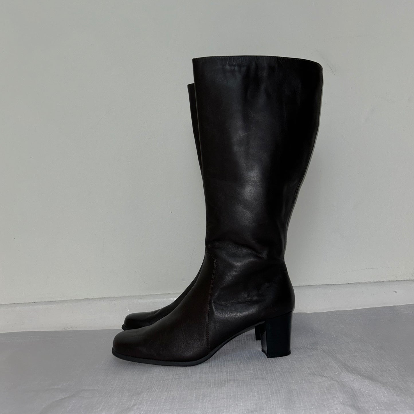 dark brown leather knee high boots shown on a white background