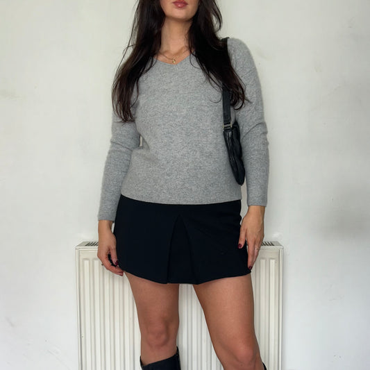 grey knit jumper shown on a model wearing a black mini skirt and black boots with a black bag