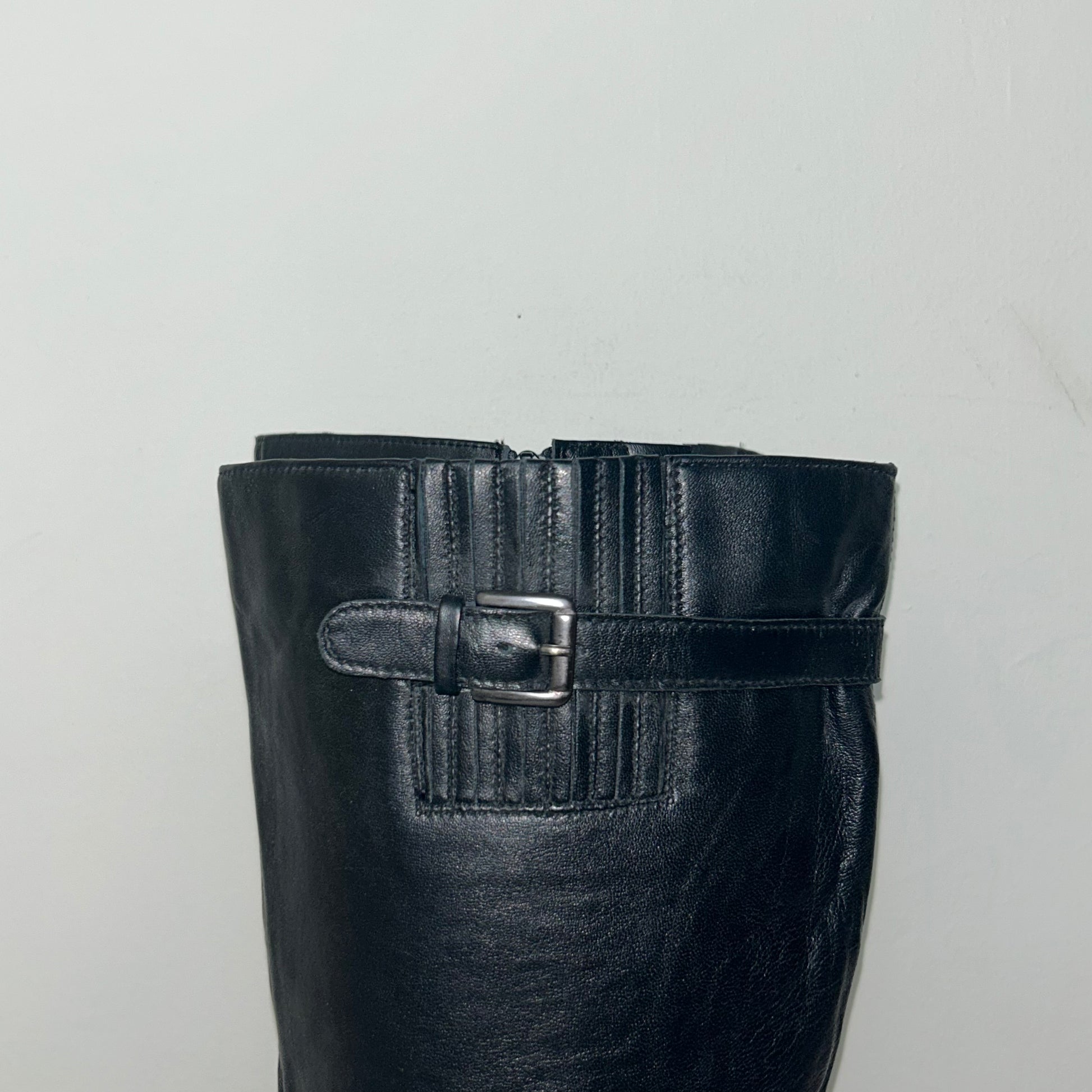 buckle of black knee high silver buckle boots shown on a white background