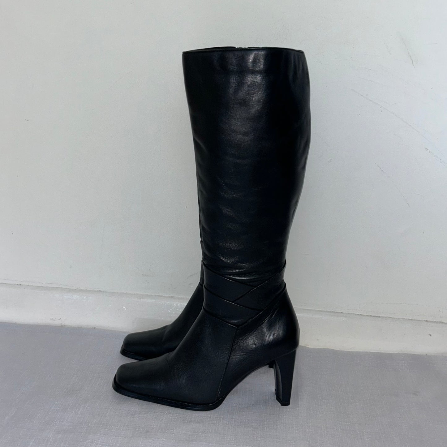 black knee high leather boots on a white background