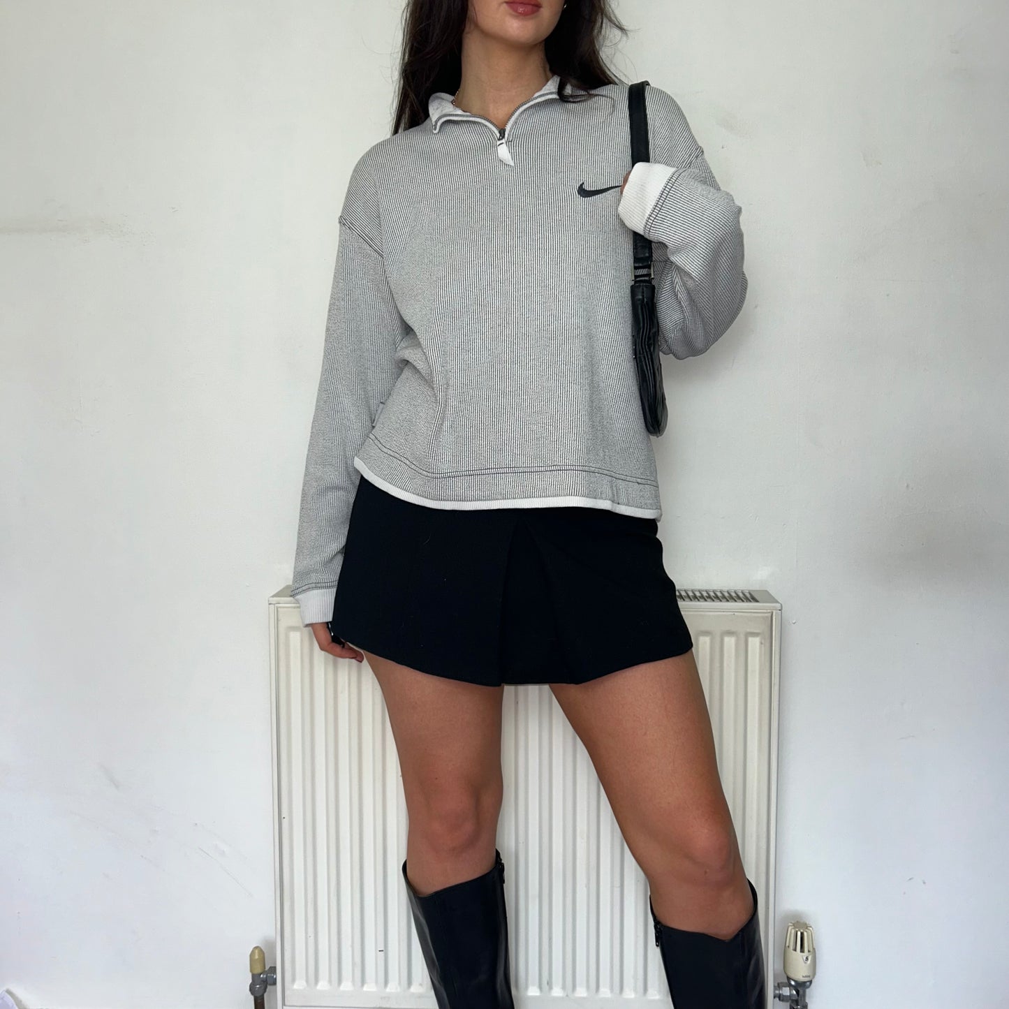 grey nike stripe 1/4 zip jumper shown on a model wearing a black mini skirt and black boots with a black shoulder bag