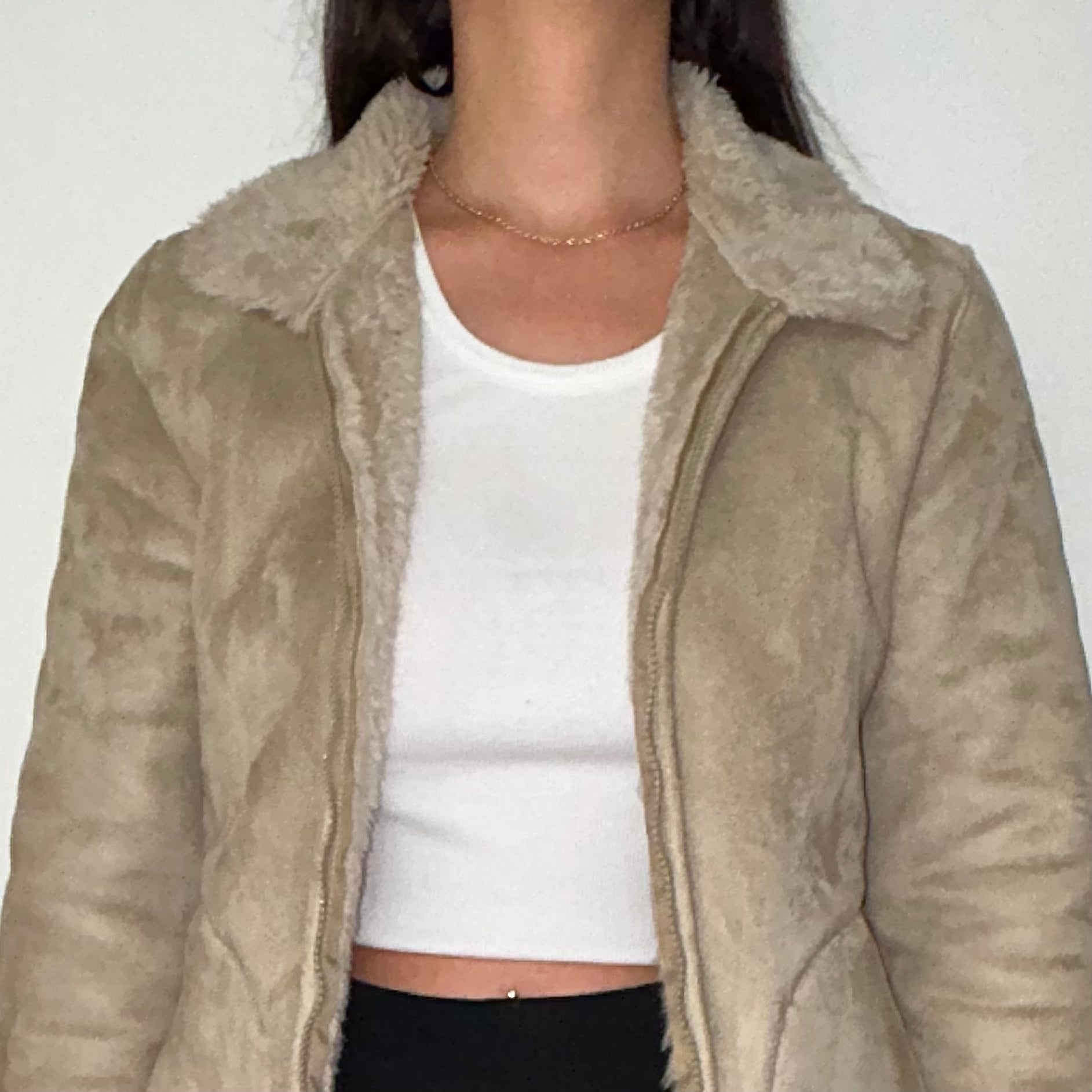 close up of beige faux fur coat shown on a model wearing a white crop top and black trousers
