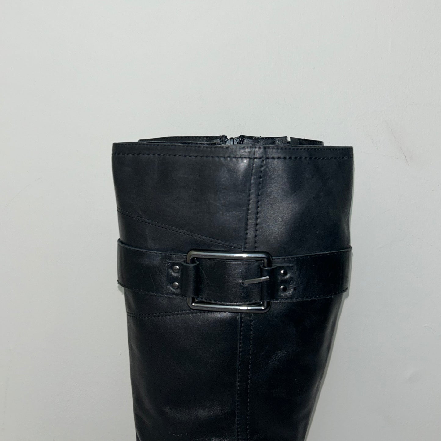 buckle of black knee high real leather boots shown on a white background