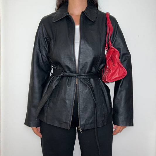 black zip up bomber jacket shown on a model wearing a white crop top and black trousers with a red shoulder bag