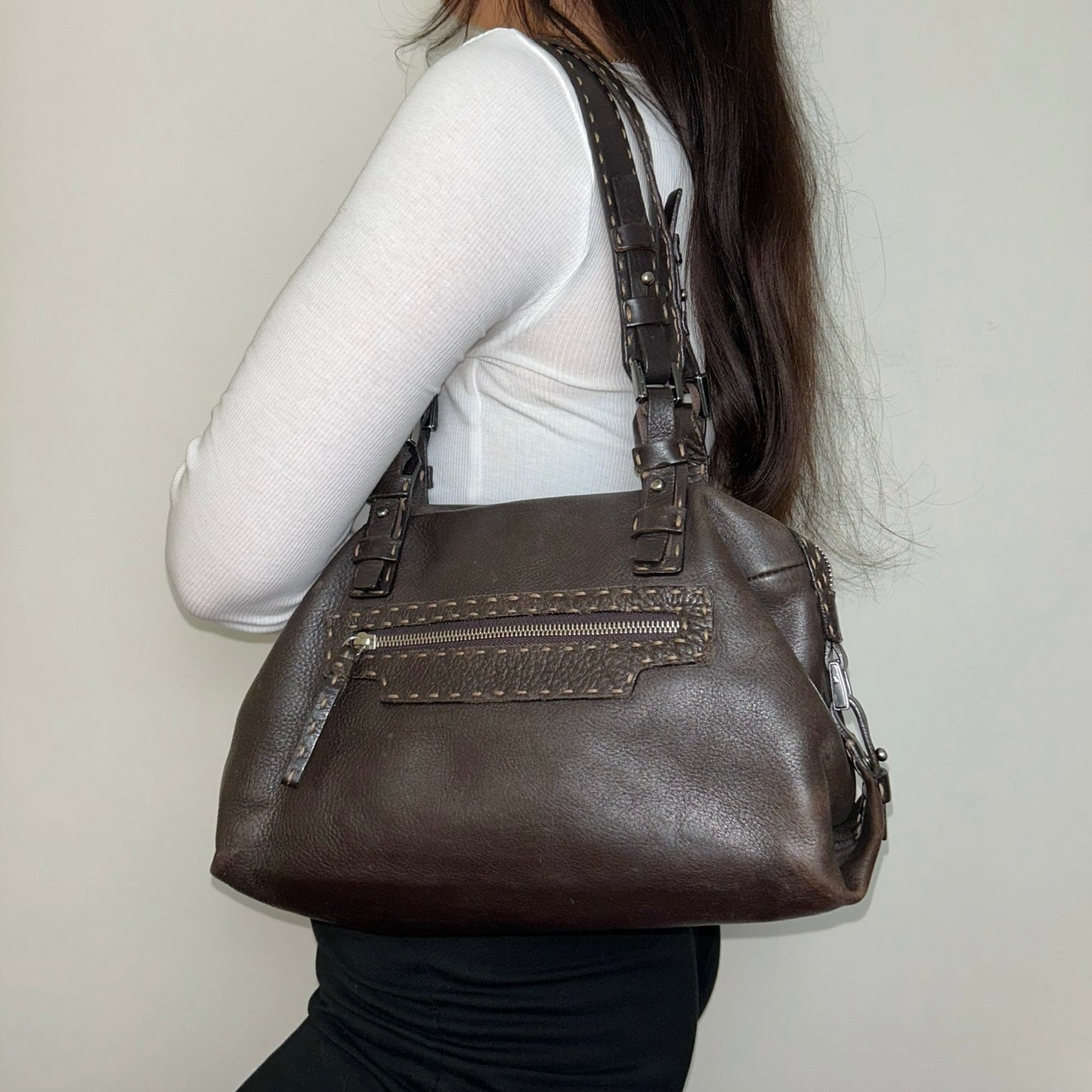 brown leather shoulder bag shown on a models shoulder