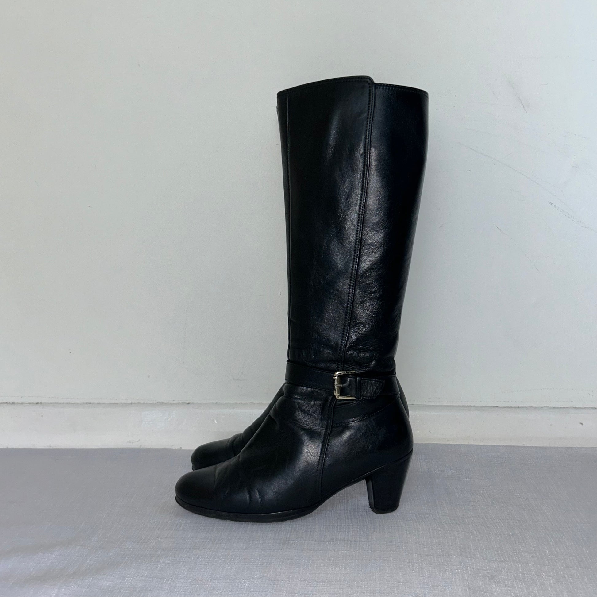 black knee high silver buckle boots shown on a white background