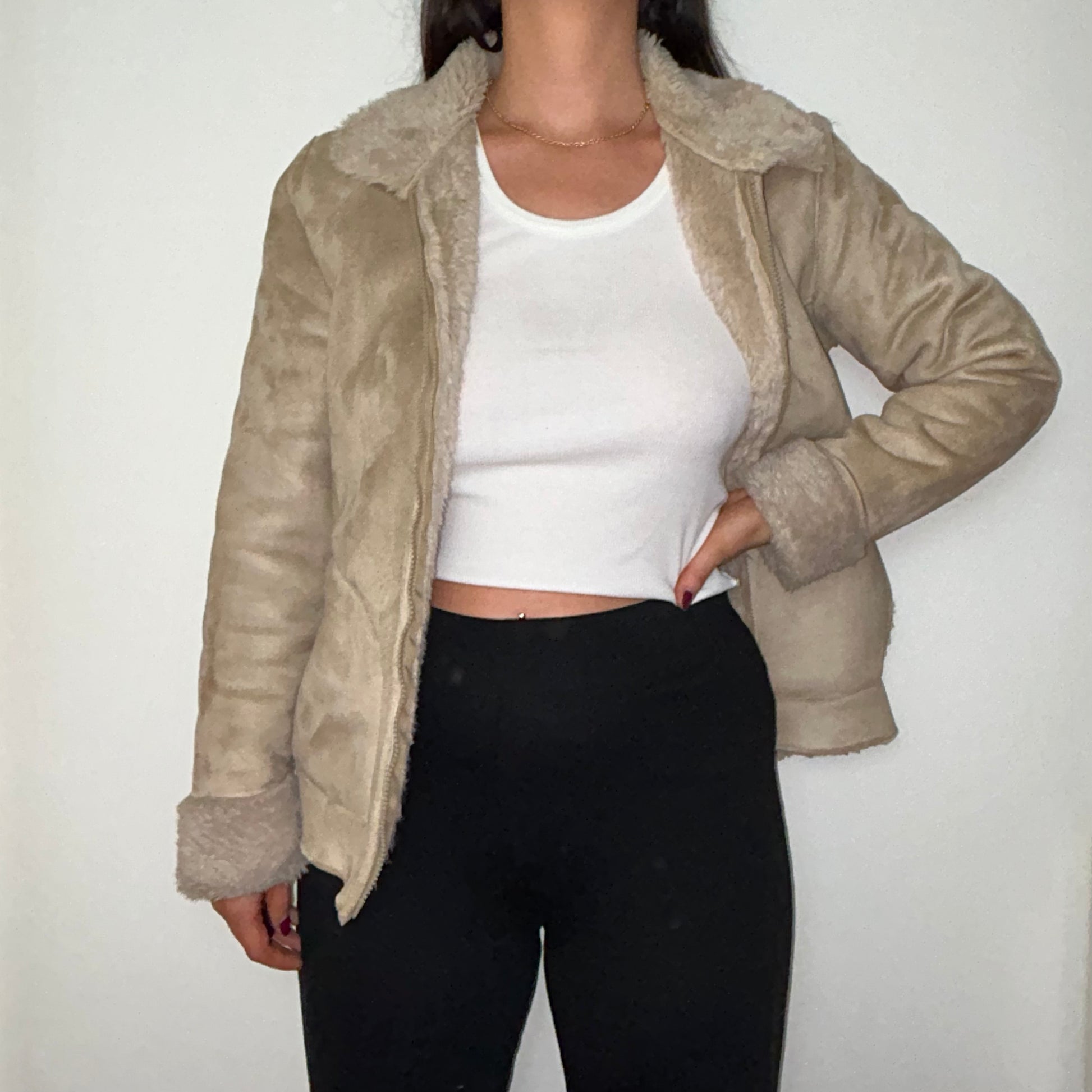 beige faux fur coat shown on a model wearing a white crop top and black trousers