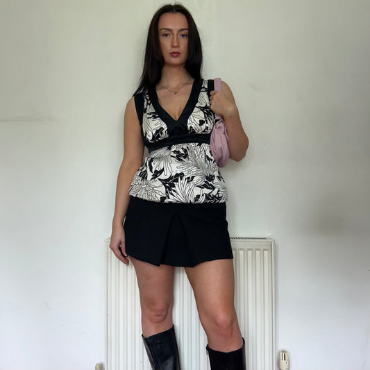 white and black vintage silk top shown on a model wearing a black mini skirt and black boots