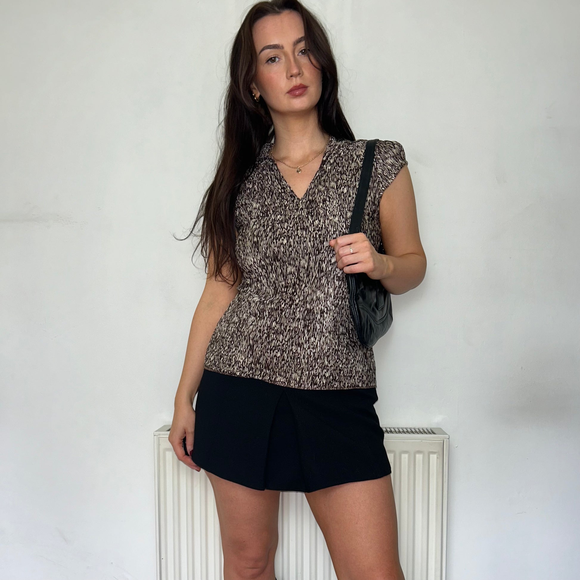 brown and beige short sleeve blouse shown on a model wearing a black mini skirt with a black shoulder bag