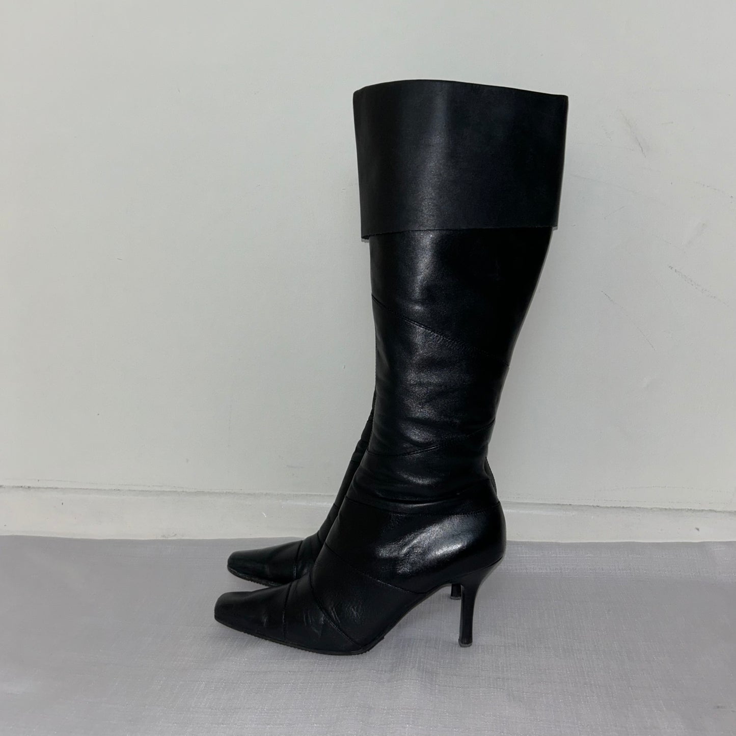 black knee high leather boots shown on a white background