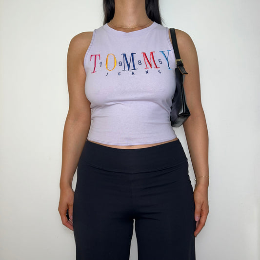 lilac short sleeve crop top with tommy jeans logo shown on a model wearing black trousers and a black shoulder bag