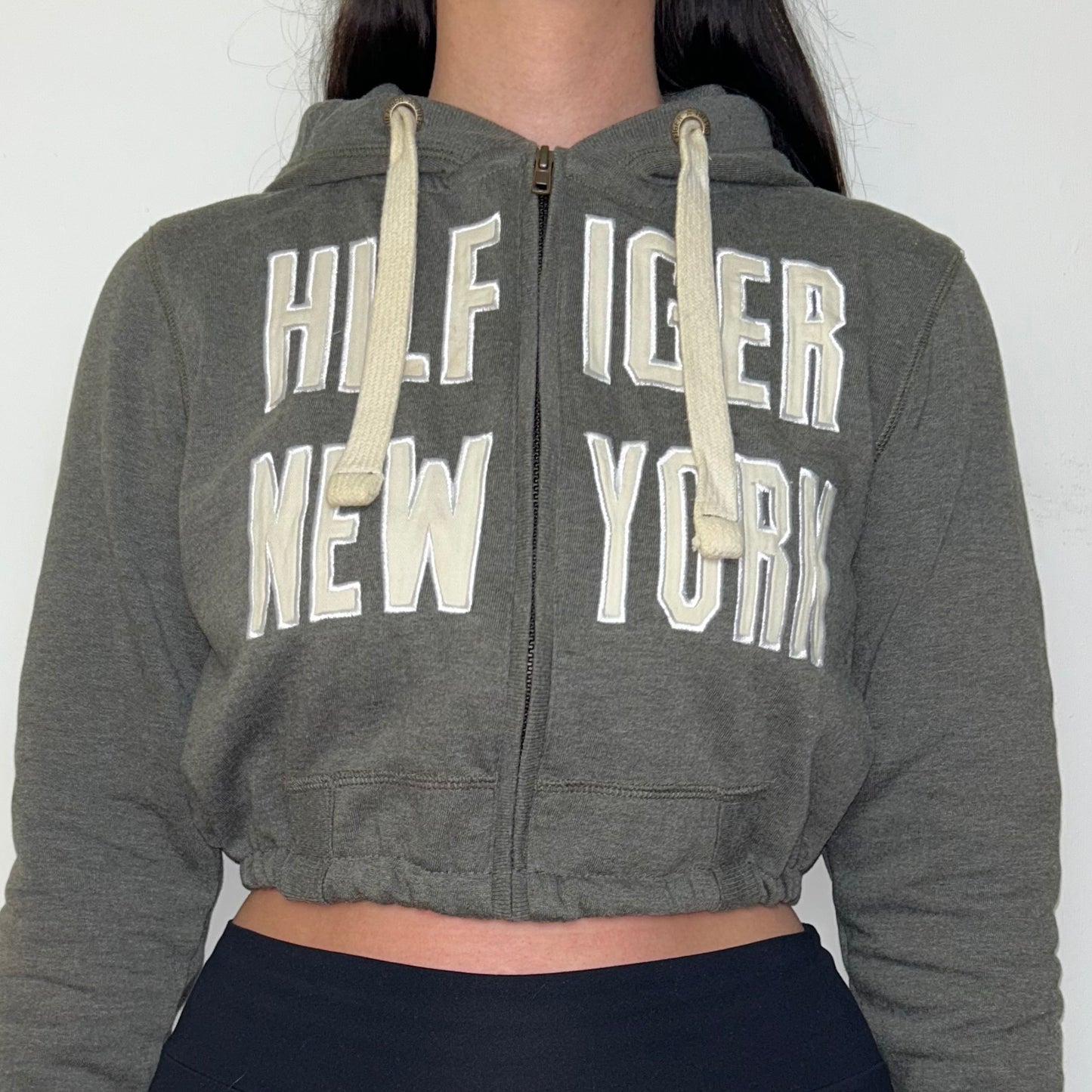 close up of grey tommy hilfiger cropped hoodie shown on a model wearing black trousers