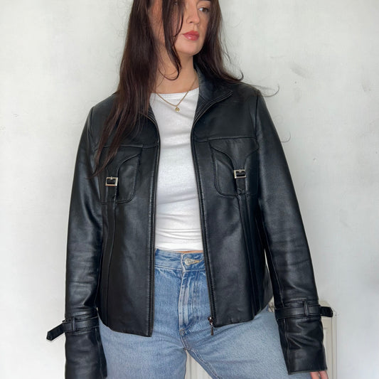 black leather buckle bomber jacket shown on a model wearing a white crop top and blue jeans