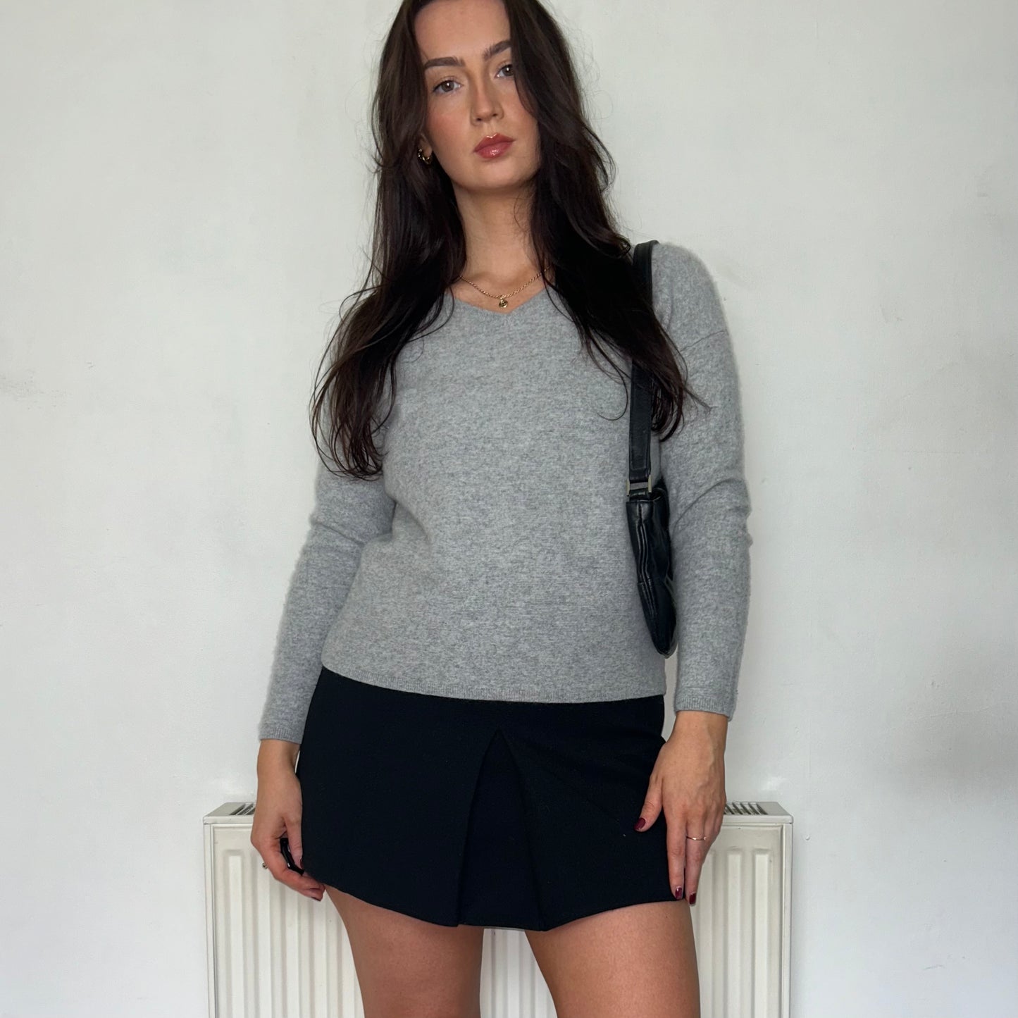 grey knit jumper shown on a model wearing a black mini skirt with a black bag