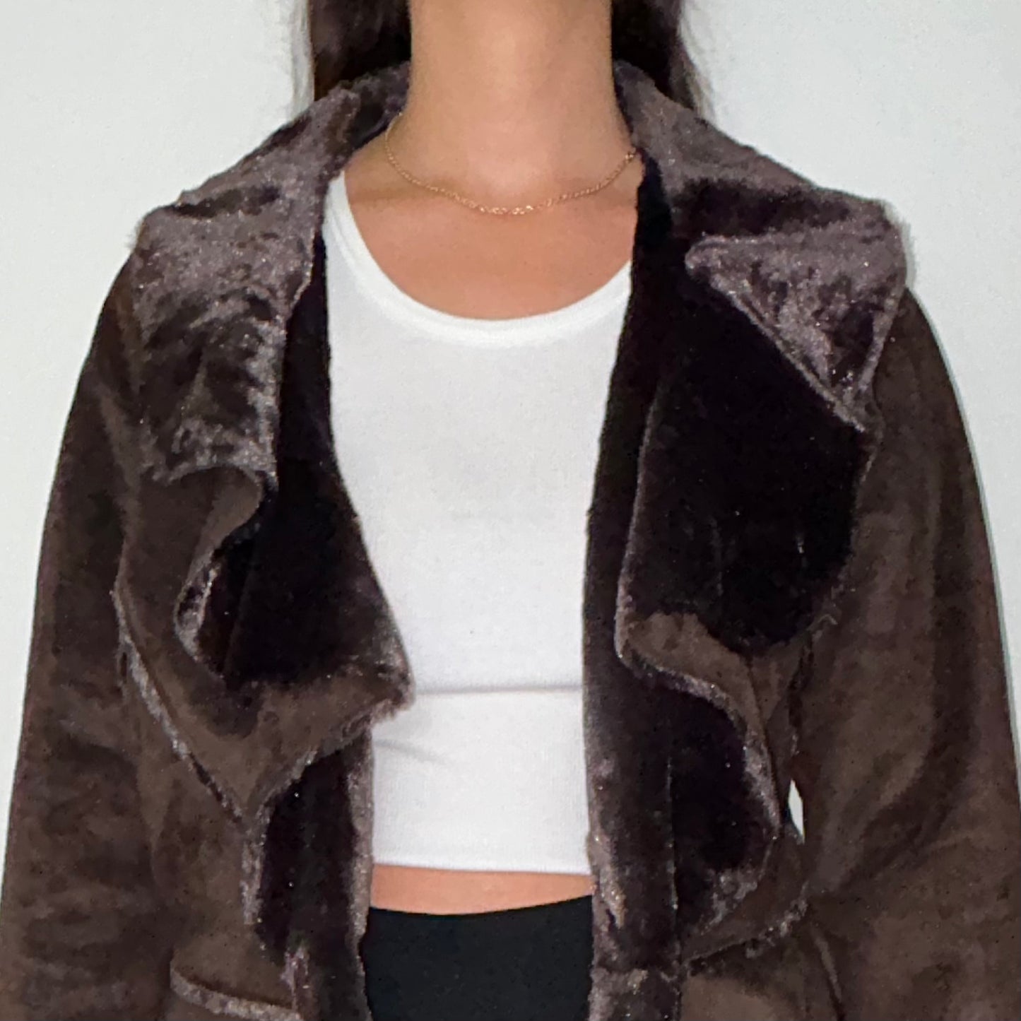 close up of brown faux fur coat shown on a model wearing a white crop top and black trousers