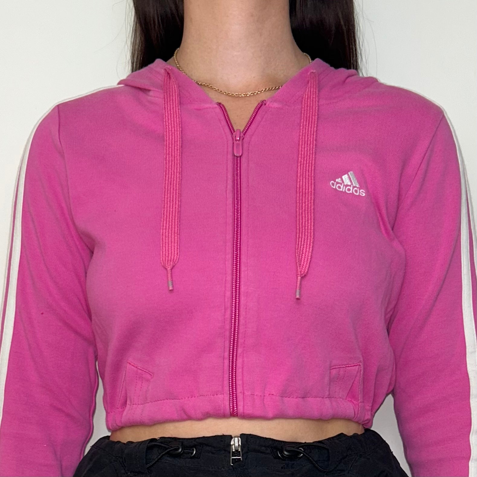 close up of pink zip up hoodie with white adidas logo shown on a model