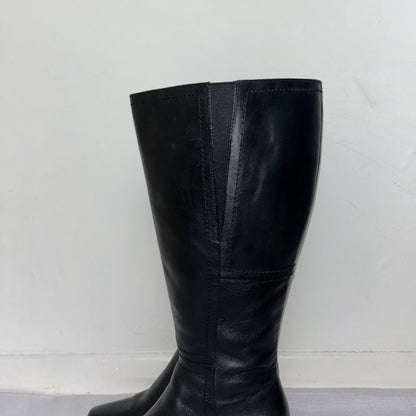 close up of black knee high leather boots shown on a white background