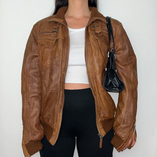 tan brown leather jacket shown on a model wearing a white crop top and black trousers and a black shoulder bag
