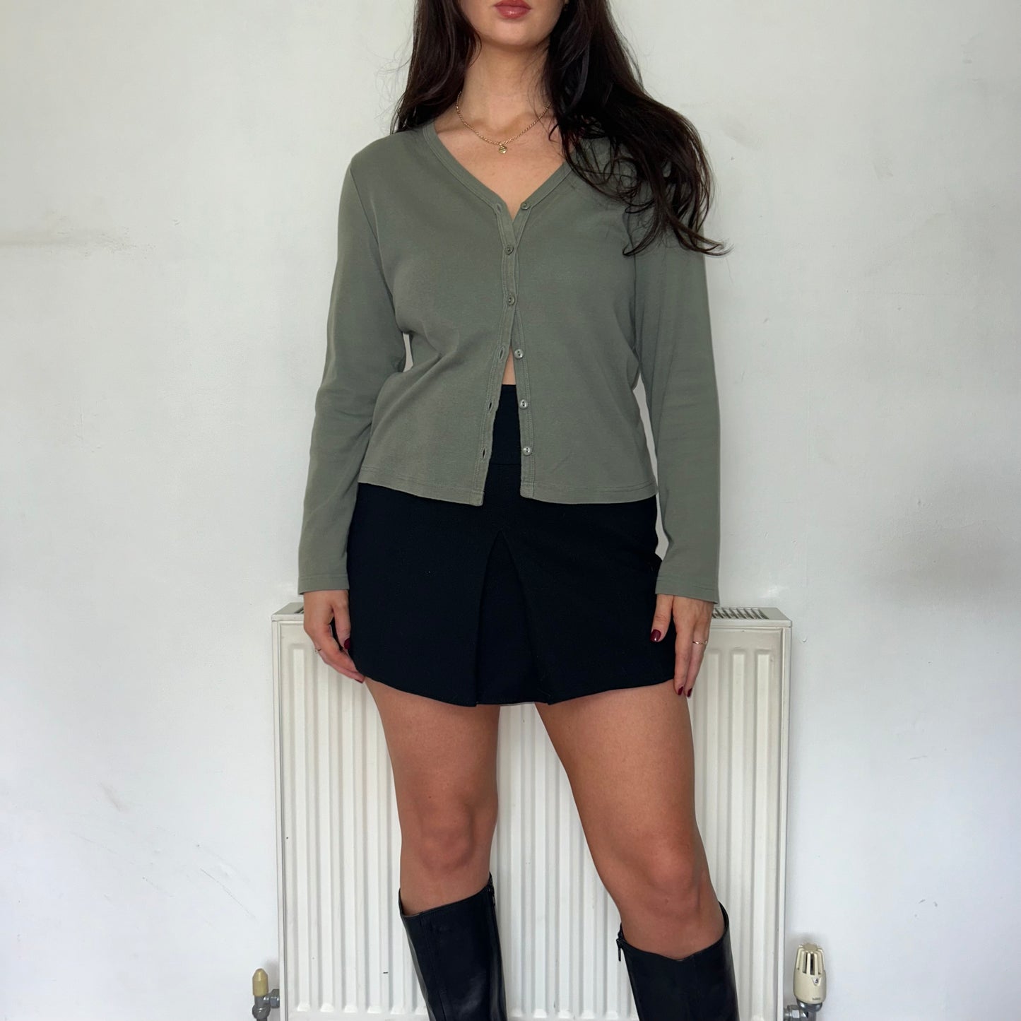 green button up long sleeve top shown on a model wearing a black skirt and black boots