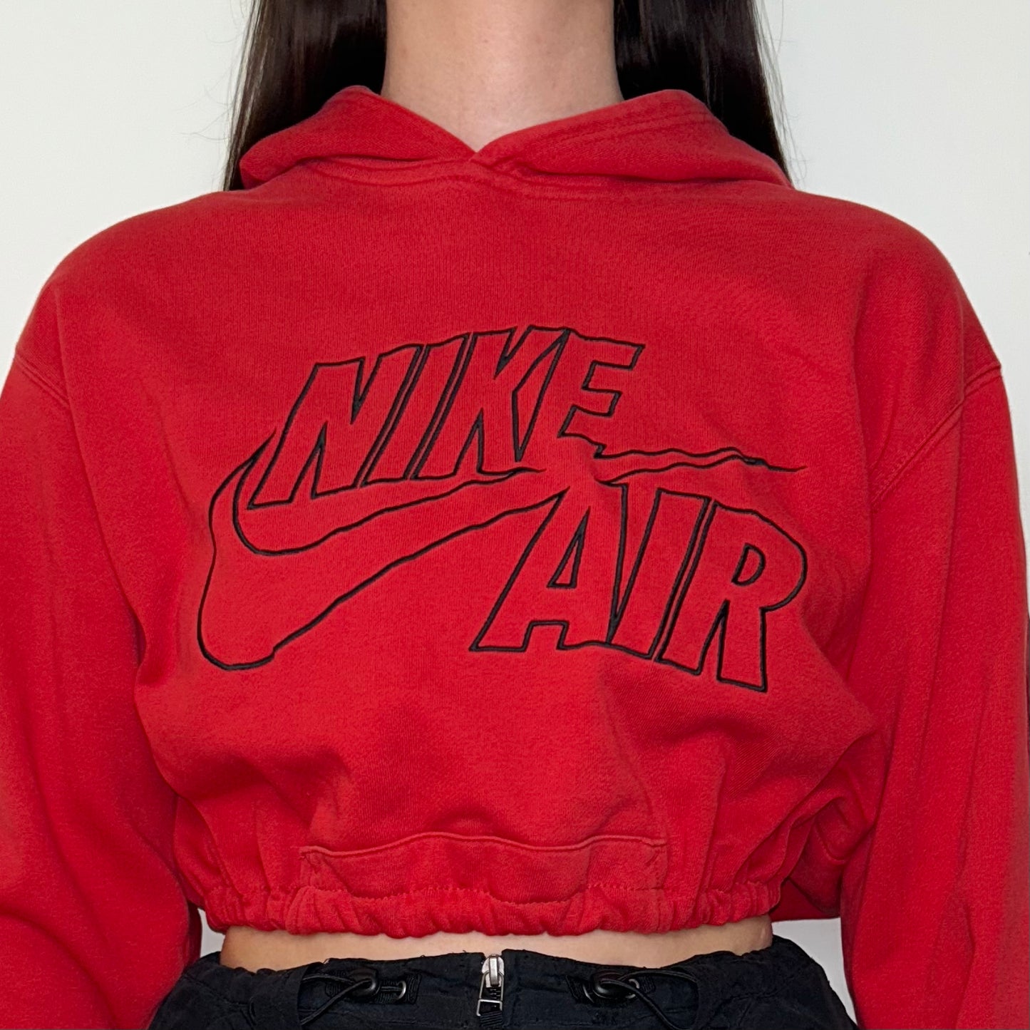 close up of red cropped hoodie with black nike air logo shown on a model